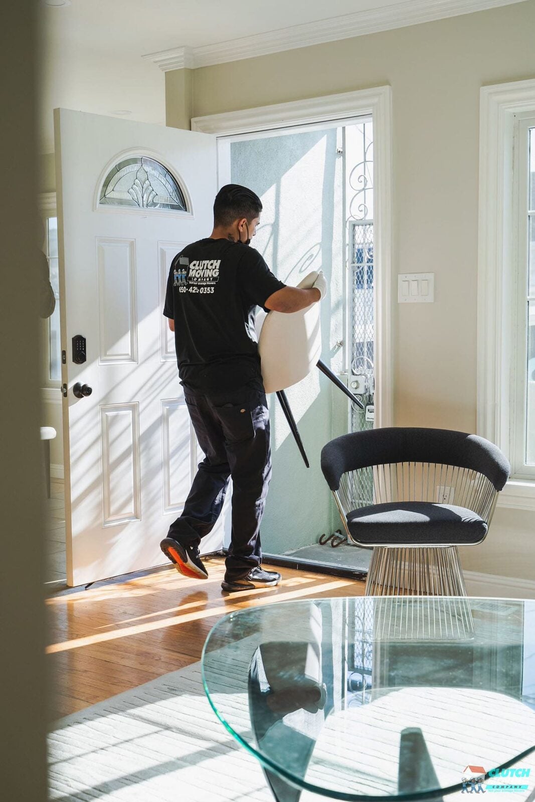 Worker carrying a rolled-up rug inside a home, wearing a Clutch Moving Company shirt.