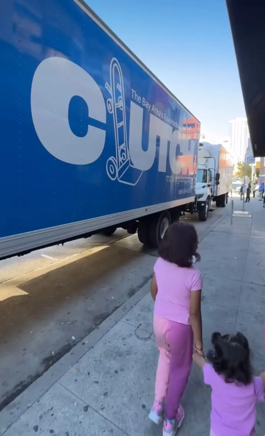Family walking past a Clutch Moving Company truck on moving day